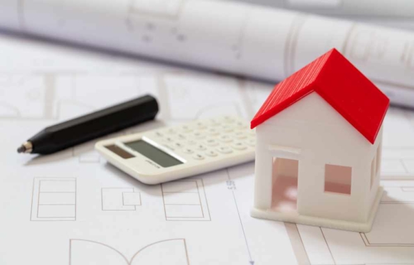 Calculator and house model on blueprint background. Construction cost concept.